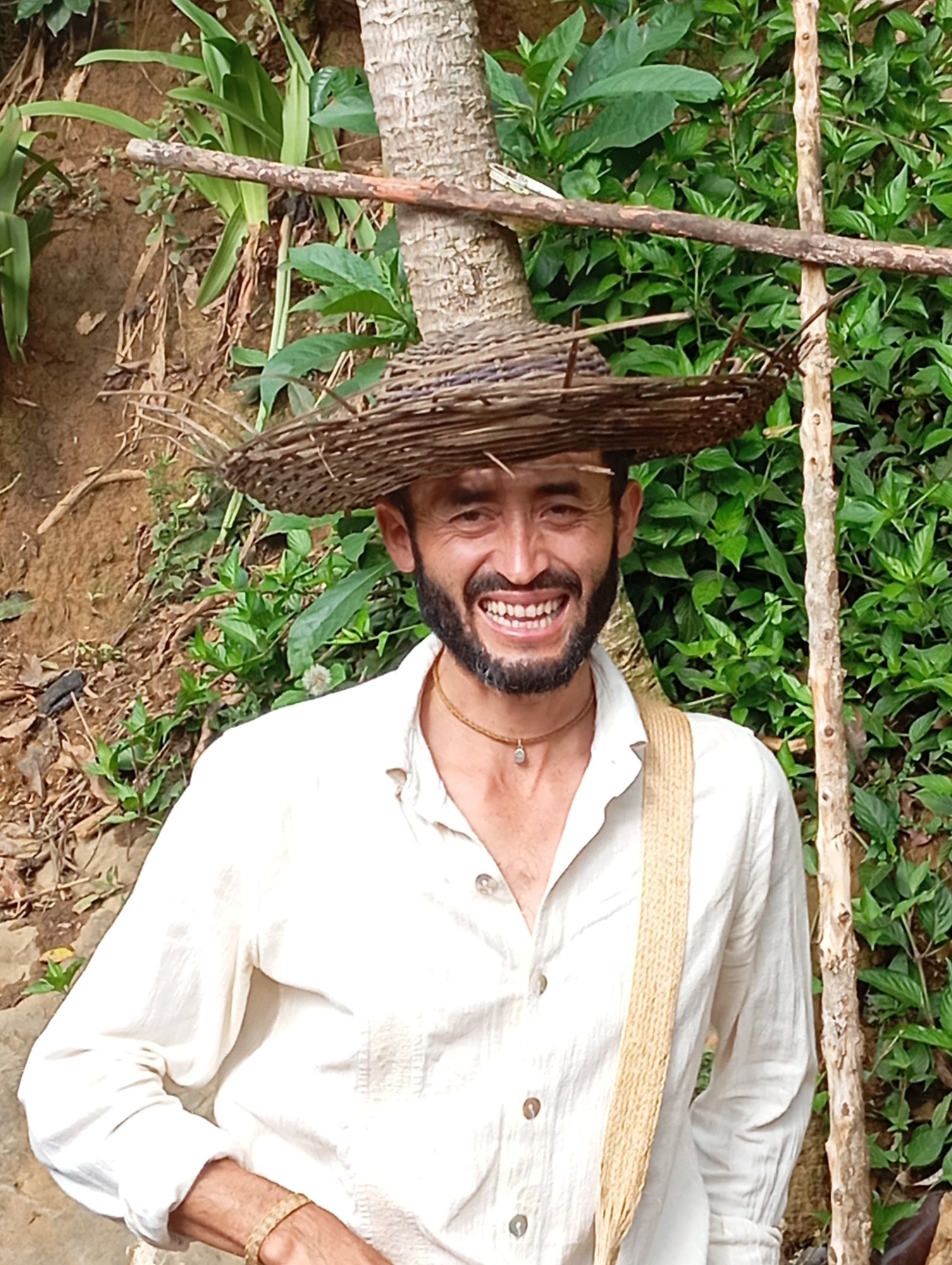 Albeiro sonriente en el campo, con sombrero y mochila tejidos por él mismo